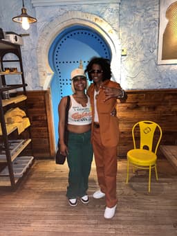 kidd and her sister, taylor, embrace and smile at the camera in front of a blue Moorish door at a downtown NYC restaurant