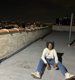 kidd sits on a rooftop at nigth and looks up at the camera